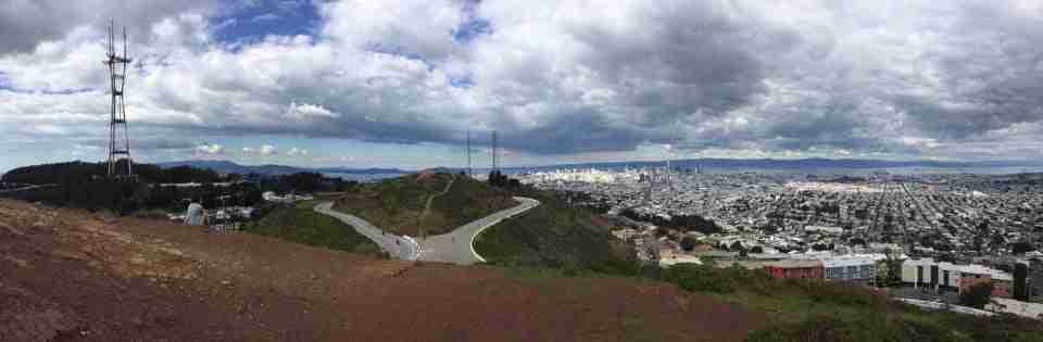 Panoramic photo of the view from Twin Peaks South Peak of Sutro Tower, distant Marin hills, the Golden Gate Bridge, downtown San Francisco, neighborhoods, East Bay hills, the bay with tiny container ships and the the idling Grand Princess.