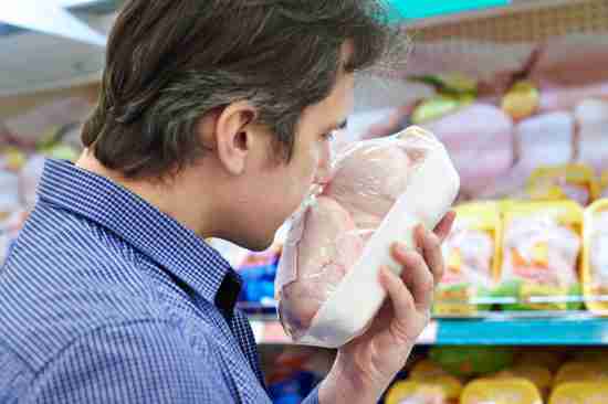 Buyer sniffing chicken in store, checking freshness
